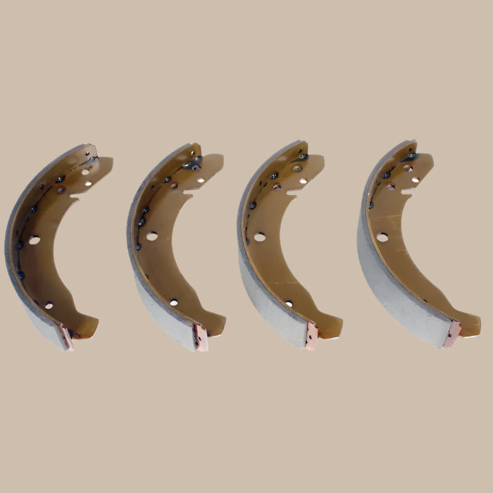 Four metal brake shoes on a beige background