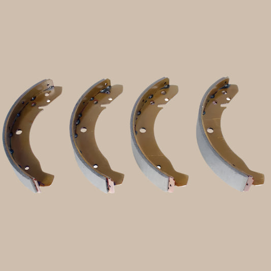 Four metal brake shoes on a beige background